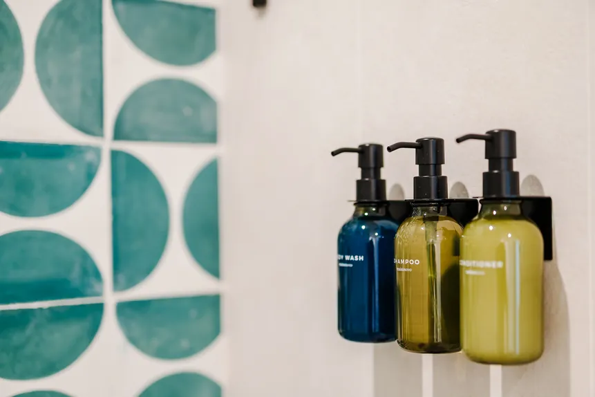 Refillable bath amenities against green tile