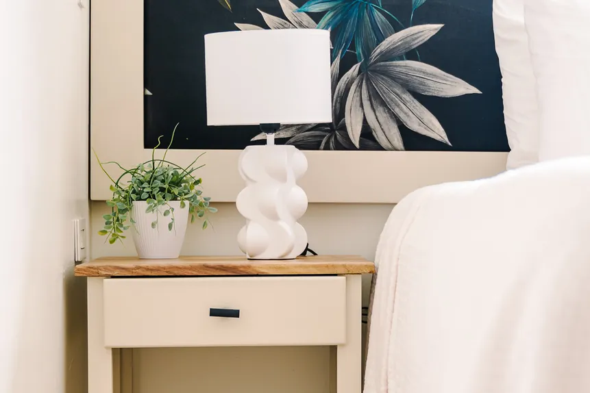 Nightstand with lamp and books beside the king bed